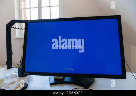 Paris, France - Sep 7, 2020: Creative table with large Nec Spectraview Reference monitor showcasing THis might take several minutes text during Microsoft Windows blue screen update Stock Photo
