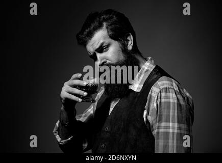 Bartender leather apron holding whisky cocktail in glass. Bearded and glass of whiskey. Stock Photo