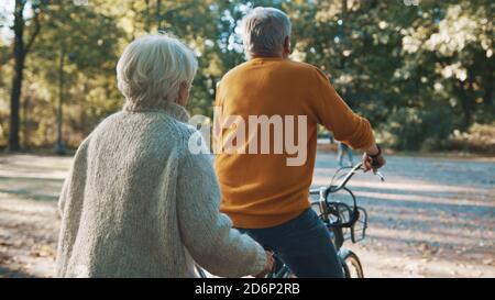 Senior couple riding double bicycle in autumn. Grandmother and grandfather cycling together . Elderly people healthy and active lifestyle. High quality photo Stock Photo
