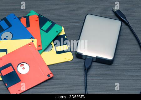 Modern hard drive and colorful retro floppy disks computer technology Stock Photo