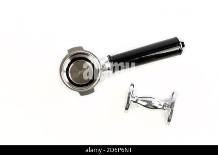 Black and silver coffee filter holder with a metal coffee tamper close by Stock Photo