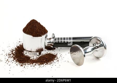 Black and silver coffee filter piled high with grounds sitting next to a tamper Stock Photo