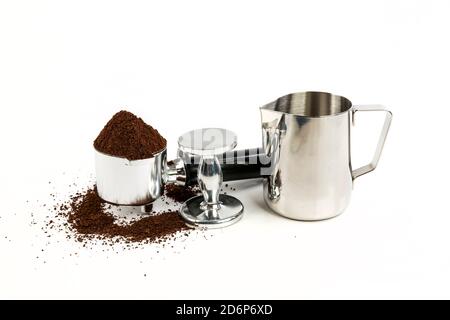 Black and silver coffee filter piled high with grounds sitting next to a tamper and milk steamer cup Stock Photo