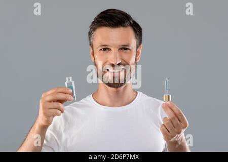 Middle-aged good looking man holding bottle with serum Stock Photo