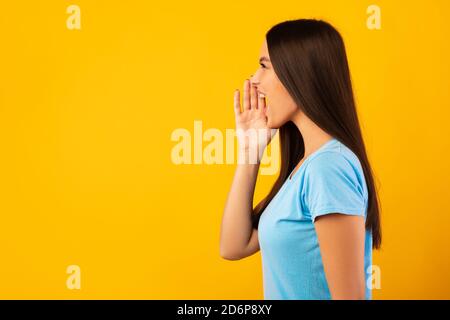Lady holding palm near mouth, screaming aside at copyspace Stock Photo