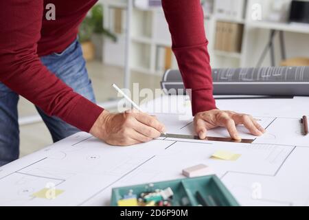 Close up of unrecognizable architect drawing blueprints while leaning on desk at workplace, copy space Stock Photo