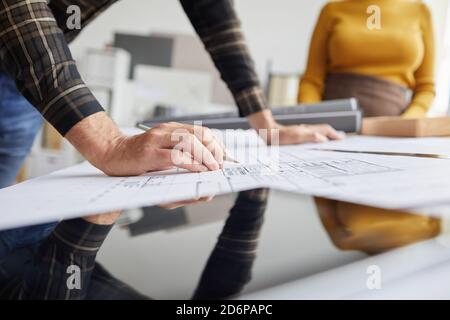 Close up of unrecognizable male architect drawing blueprints while working at desk in office, copy space Stock Photo
