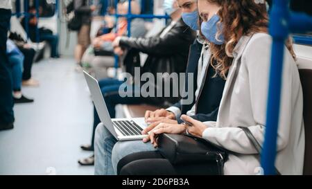 young couple with a laptop sitting in a subway car. Stock Photo