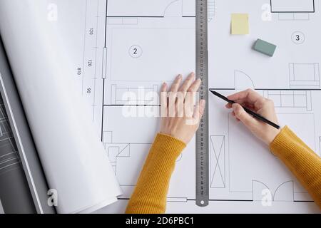 Top view close up of female architect drawing blueprints and plans while sitting at desk in office, copy space Stock Photo