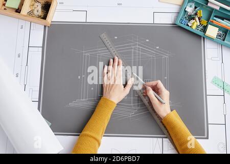 Above view close up of female architect drawing blueprints and plans while sitting at desk in office, copy space Stock Photo