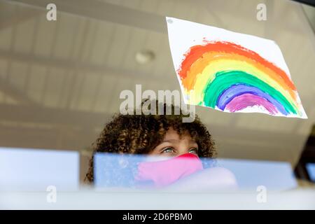 Boy wearing face mask looking out to the window Stock Photo