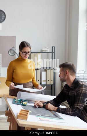 Vertical portrait of two architects discussing blueprints while working together in office Stock Photo