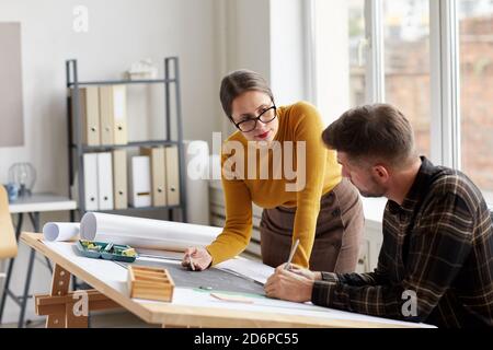 Portrait of two architects pointing at floor plan while working on blueprints at workplace, copy space Stock Photo