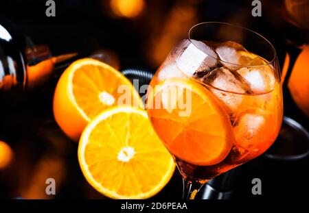 Aperol spritz cocktail in big wine glass with orange and ice, summer alcoholic cold drink, dark bar counter with steel bar tools, copy space Stock Photo