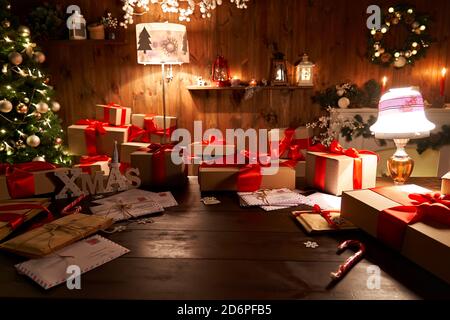 Santa workshop table with Merry Christmas tree, gift boxes pile on xmas night. Stock Photo