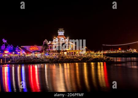 Night photo of popular Shoreline Village and the RMS Queen Mary, with colored lights reflecting on the water. Stock Photo