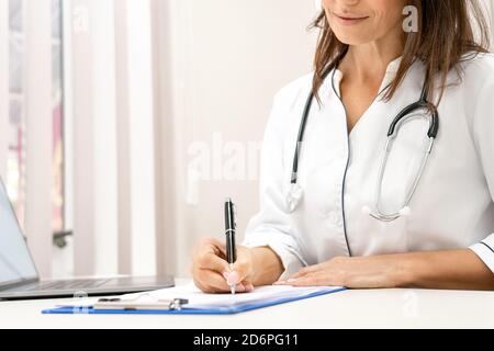 Close-up view on female doctor writing on clipboard. Stock Photo