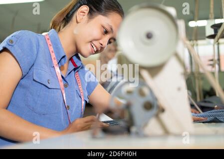 close up of a beautiful woman smiling while sewing using a sewing machine Stock Photo