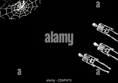 Halloween decoration card with skeletons for celebration design. Black background. Flat lay. Place for text.