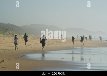 Active people on beach, moody atmosphere of Umhlanga Rocks waterfront, Durban, South Africa, health activities, seaside attraction, walking, running Stock Photo