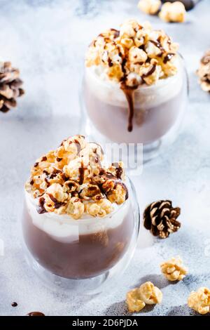 Cold winter chocolate dessert with whipped cream, popcorn and caramel topping in glasses on beige background, place for text Stock Photo