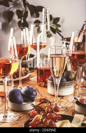 Rose wine glasses and bottles on table served for festive dinner party with different kinds of appetizers and fruits Stock Photo