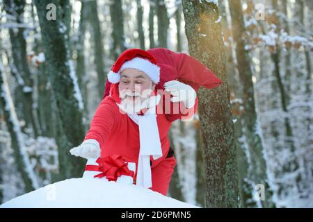 Santa Claus walking to the winter forest with a bag of gifts, snow landscape. Happy New Year. Stock Photo