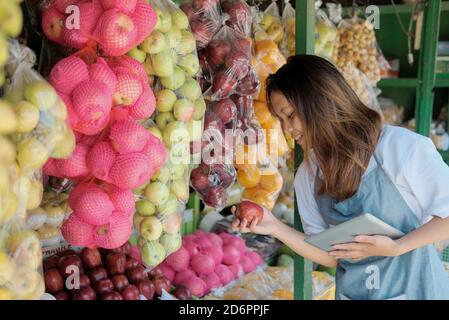 Close up of female shop assistant using digital tablet at his fruits shop when preparing Stock Photo