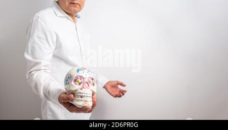 Isolated man on a white background shows a skull painted on the day of the dead or halloween. Selective focus Stock Photo