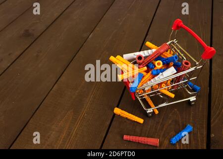 Miniature red shopping cart model with plastic dowels on wood background Stock Photo