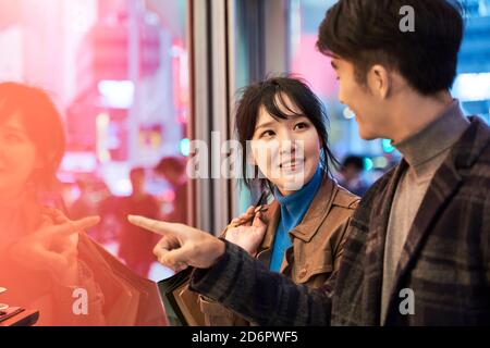 loving young asian couple looking at shop window and talking happy and smiling Stock Photo