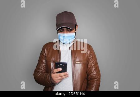 Handsome young man wearing facemask and brown leather jacket Stock Photo