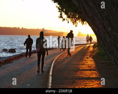 October 2020, Vancouver, Canada - People walking, running and jogging along the Stanley Park seawall. Anchored ships visible in the background. Stock Photo