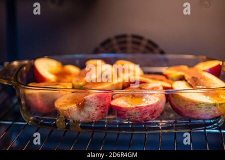 glass container with sliced stuffed apples in the oven, close-up, homemade dessert concept Stock Photo