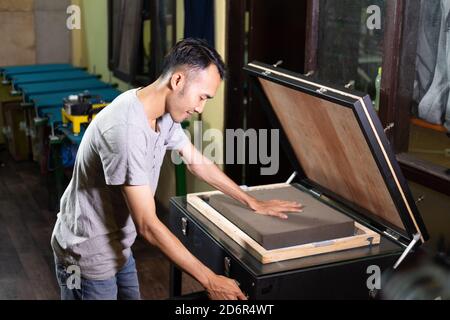 asian man working pressing a sponge to make film on silk screen surface Stock Photo