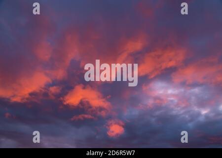 Gloomy sunset sky with red clouds illuminated by the setting sun Stock Photo