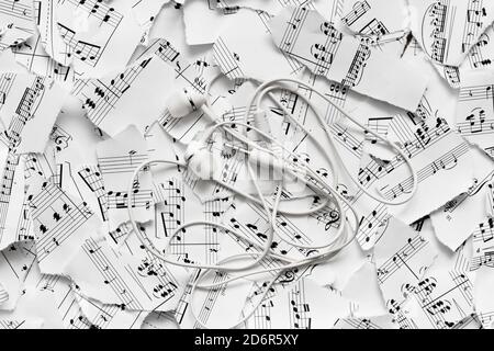 White headphones on the background of notes. Listening to music Stock Photo