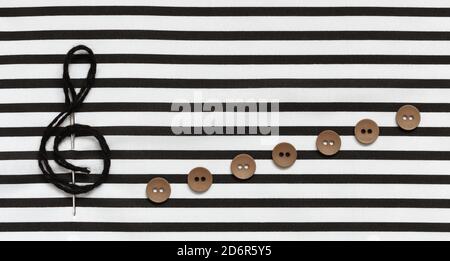 Treble clef, needle and buttons on fabric with stripes. Stock Photo