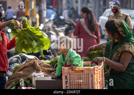 Dehradun, Uttarakhand/India-October 14 2020:A poor women selling vegetables on push cart with her cute little child in basket in India. High quality photo Stock Photo