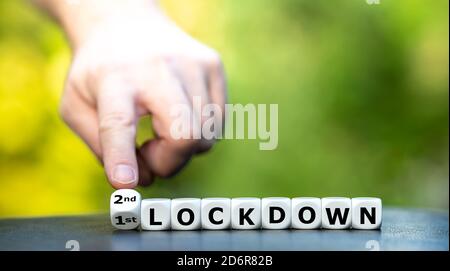 Symbol for a second lockdown. Hand turns dice and changes the expression "1st lockdown" to "2nd lockdown". Stock Photo