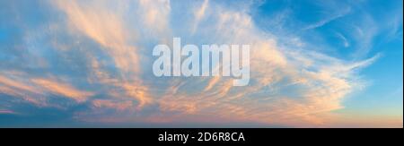 Majestic vanilla sky at evening. Azure sunset heaven with golden pink cirrus clouds over the horizon. Panoramic shot of pastel colored skyscape. Stock Photo