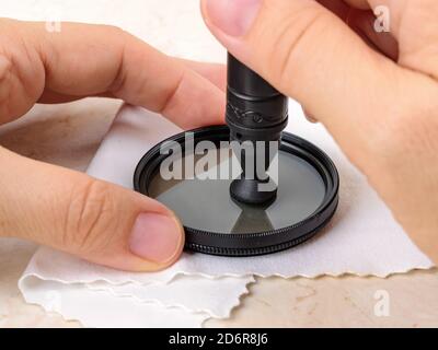 Hands polish camera polarizing filter using lens pen soft felt end over microfiber cloth. Removal of dust and fingerprints from photographic equipment Stock Photo