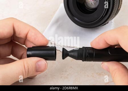 Hands removing a cap from a lens pen before cleaning a camera lens. Routine removal of dust and fingerprints from photographic equipment. Maintenance Stock Photo
