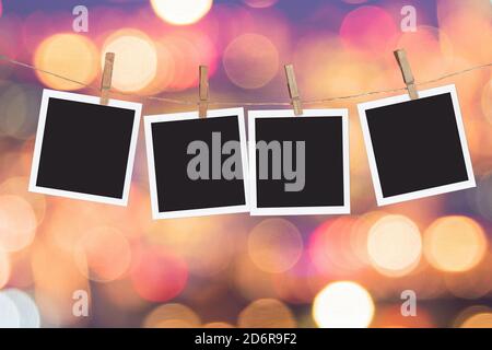 Four blank instant photo frames hanging on a rope, on holiday lights bokeh background Stock Photo