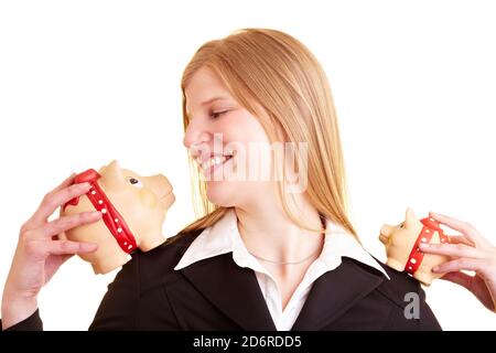 Blonde businesswoman holds two piggy banks on her shoulder Stock Photo