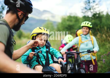 Family with tired small children cycling outdoors in summer nature. Stock Photo