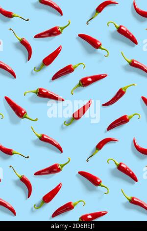 Creative background made of red chili or chilli on blue backdrop. Minimal food backgroud. Red hot chilli peppers background. Stock Photo