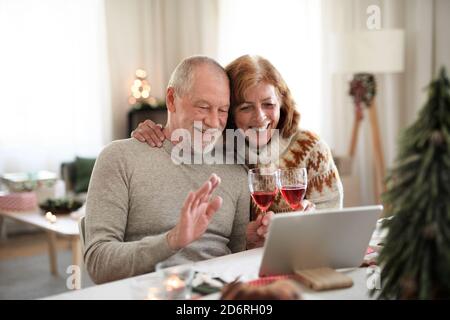 Senior couple indoors at home at Christmas, having video call with family. Stock Photo