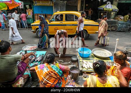 Kolkata, India - October 2020: A taxi passing in front of some stalls selling fish in the New Market on October 8, 2020 in Kolkata, West Bengala. Stock Photo