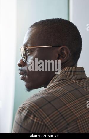 Vertical profile view portrait of smart African-American gentleman wearing glasses while looking at window, unique beauty concept Stock Photo
